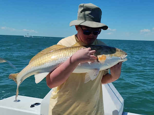 Gecko charter customers holding large red drum.