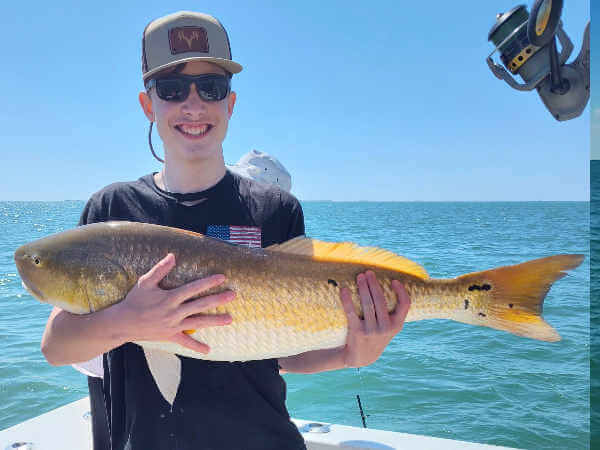 Gecko charter customers holding large red drum.