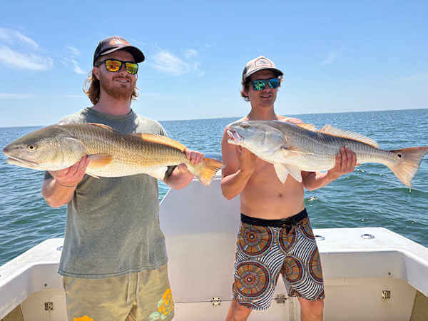 Gecko charter customers holding large red drum.