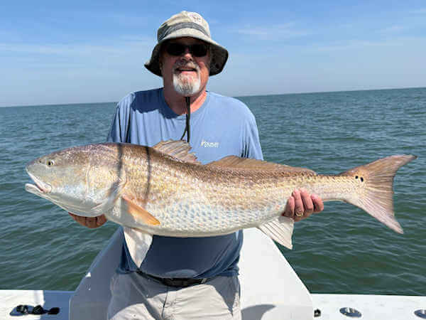 Gecko charter customers holding large red drum.