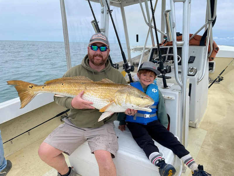 Young boy holding his first red drum.
