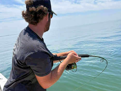 Angler fighting large red drum.