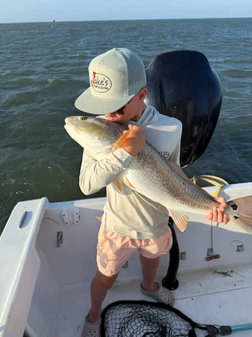 Young angler kisses giant red drum before releasing it.