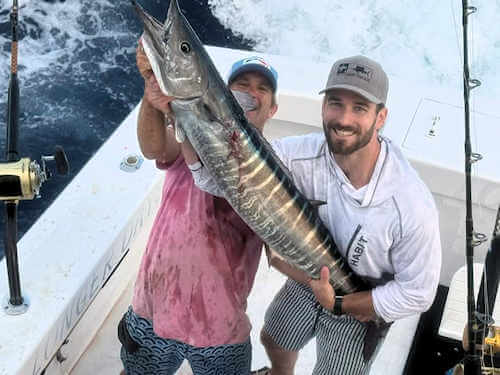 Anglers holding up a nice Hatteras wahoo on their sportfishing charter. 