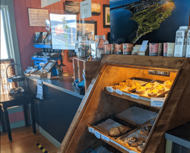 interior of Dancing Turtle shop with a display case with pastries is in the foreground. 